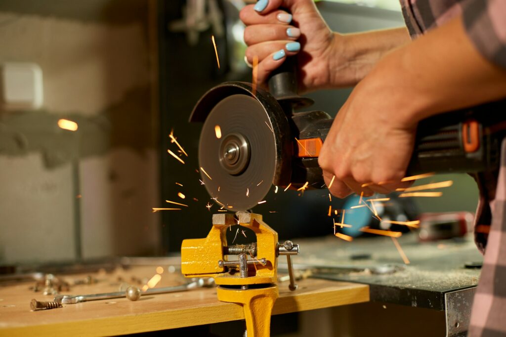 Woman locksmith works with grinder machine, fly bright sparks